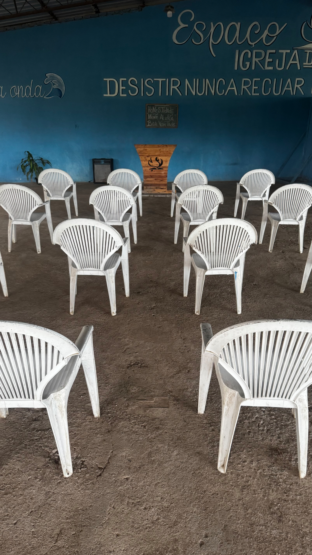 Espaço de cultos com cadeiras enfileiradas diante do púlpito de madeira