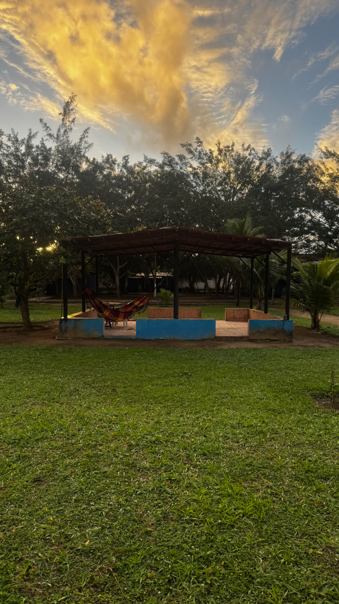Quiosque coberto com redes em meio ao gramado ao entardecer
